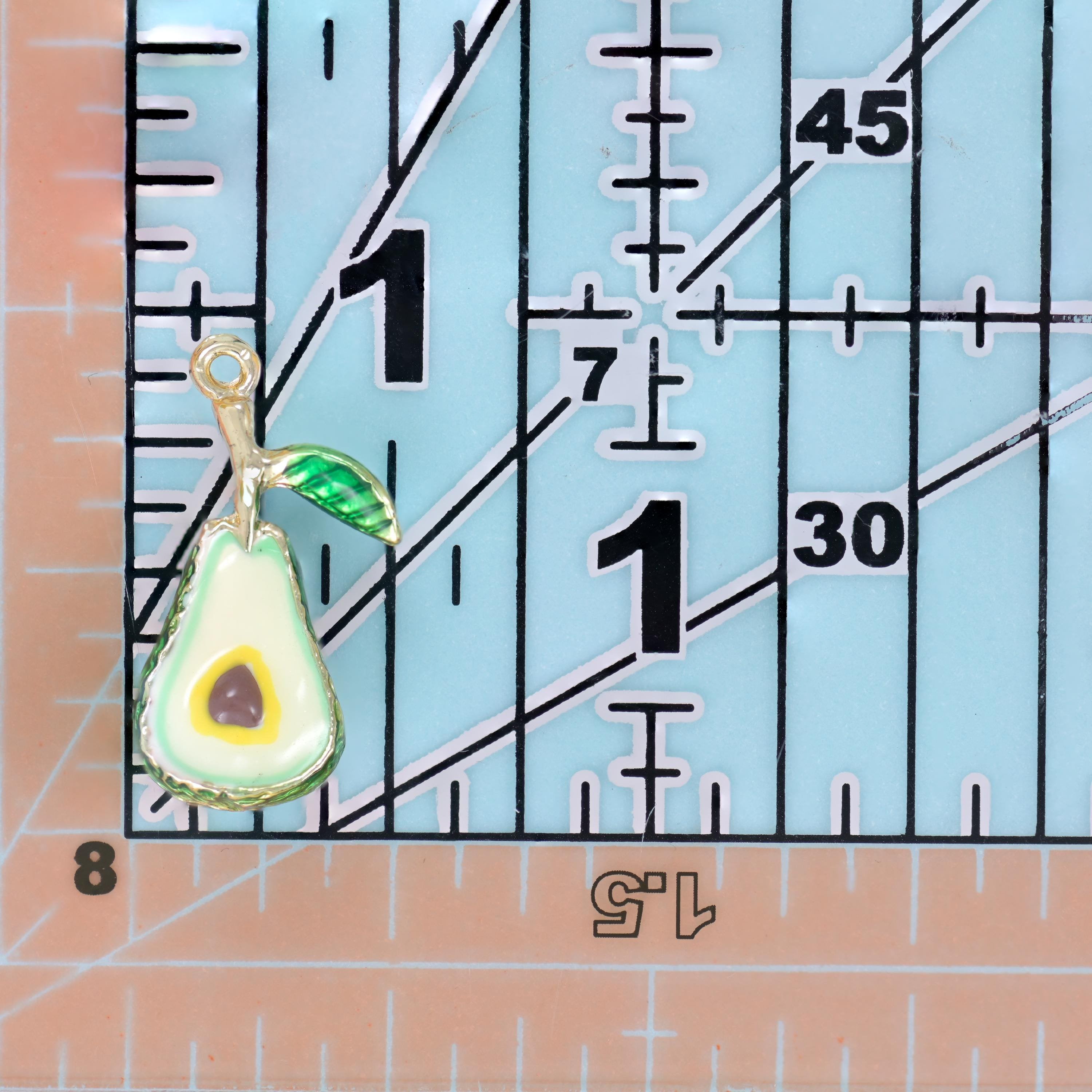 A chunky enamel avocado with a textured deep green skin and a striped green leaf on a gold stem