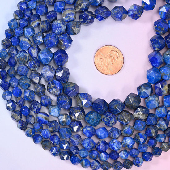 Blue Lapis Lazuli diamond star cut beads coiled around a US penny for size reference, centre drilled with a polished faceted finish