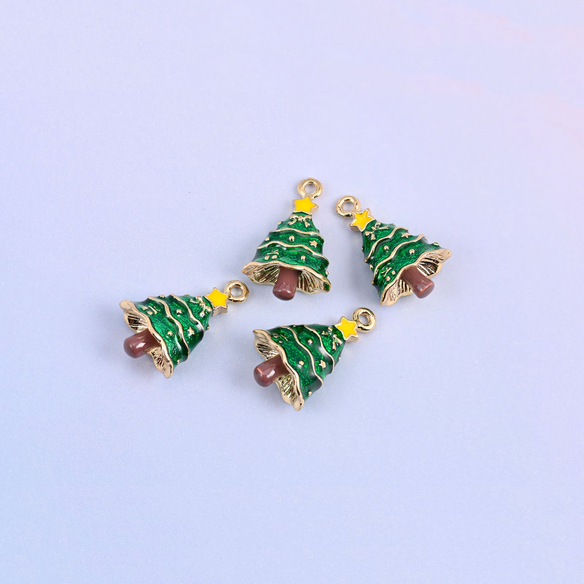 Five christmas tree charms scattered in a group, green enamel with gold garland tiers and raised gold baubles.