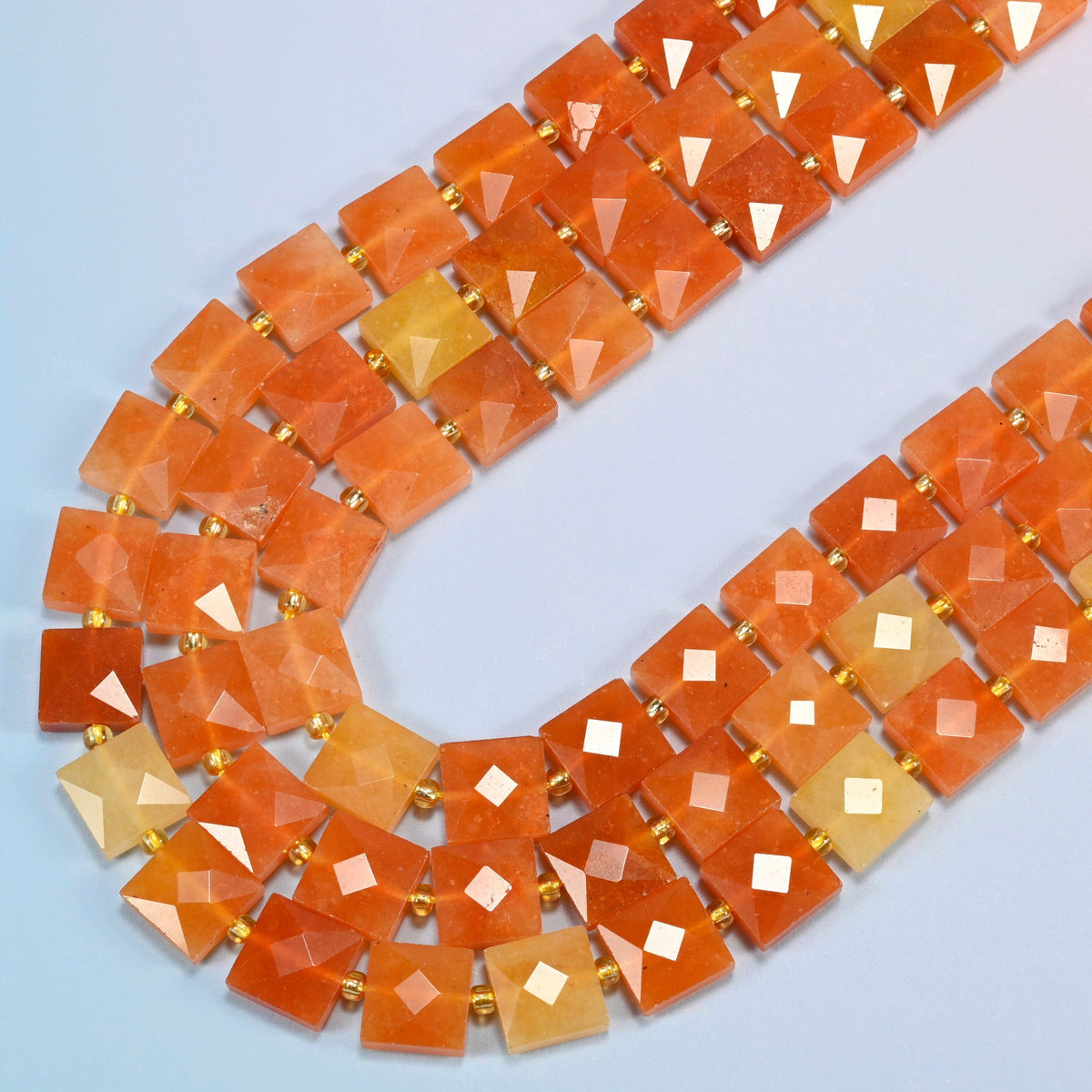 Natural red aventurine faceted flat square beads in several strands curved into a wide U, orange-red and peach orange stone
