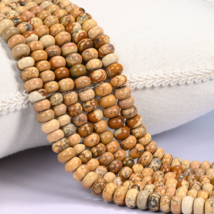 Close-up of multiple strands of polished Picture Jasper rondelle beads in tan and brown tones, draped over a cream fabric jewelry display bust.