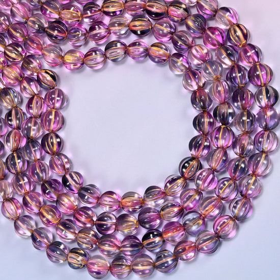 Pink blue gold pumpkin glass beads looped into one wide open ring, the strands running off both sides of the frame.