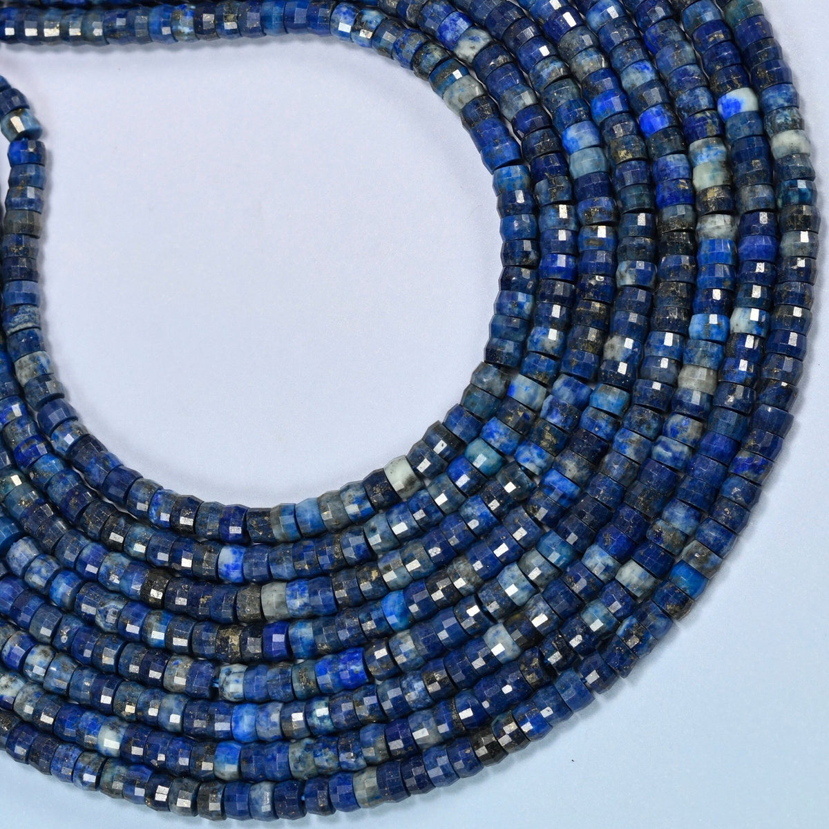 Dark blue lapis faceted heishi disc beads curved into an open loop, dark blue beads with white and gold flecks