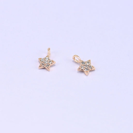 Small gold charms, two star charms with clear cubic zirconia shown close up