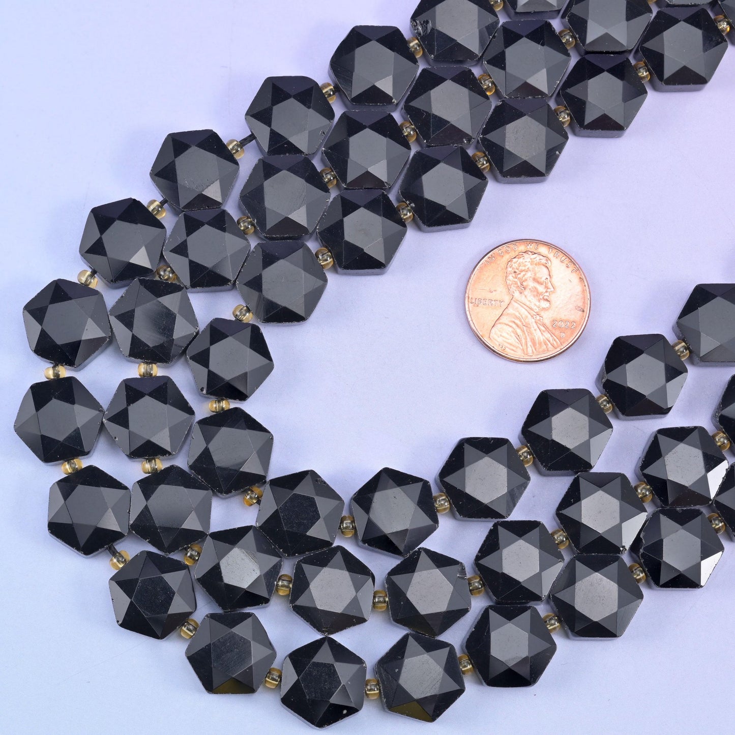 Obsidian hexagon beads looped beside a US penny for a clear sense of the 12mm size