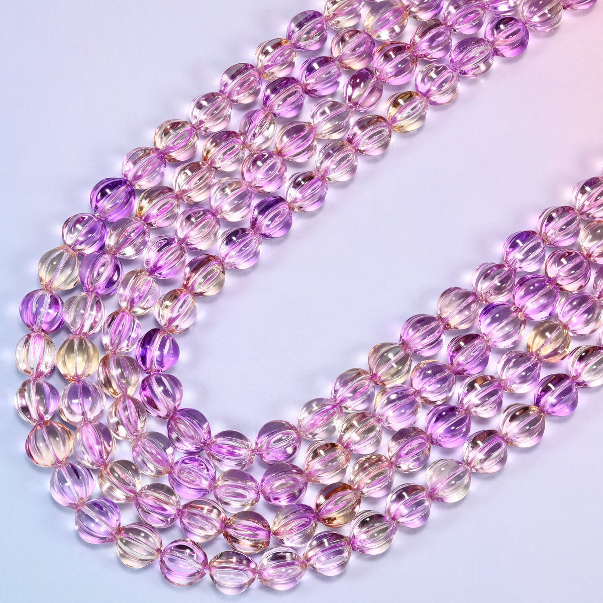 Clear purple gold pumpkin glass beads laid in a narrow chevron, the two limbs running close together down to a point.