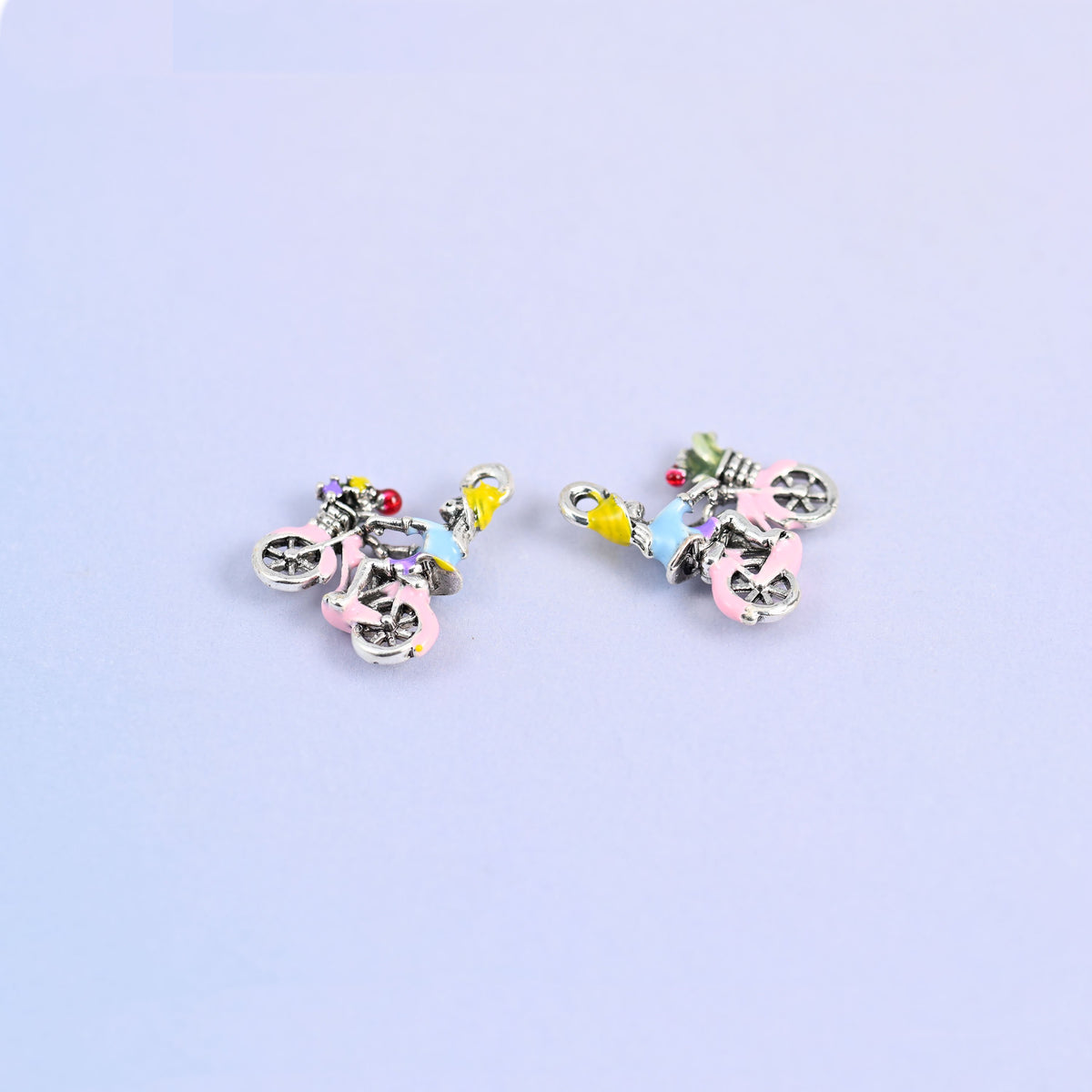 Bicycle charm next to a second turned over to show the plain white gold plated back.