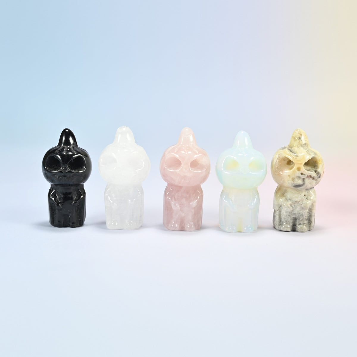 Five pumpkin skull crystal carvings: natural black obsidian, clear quartz, rose quartz and crazy agate, plus opalite