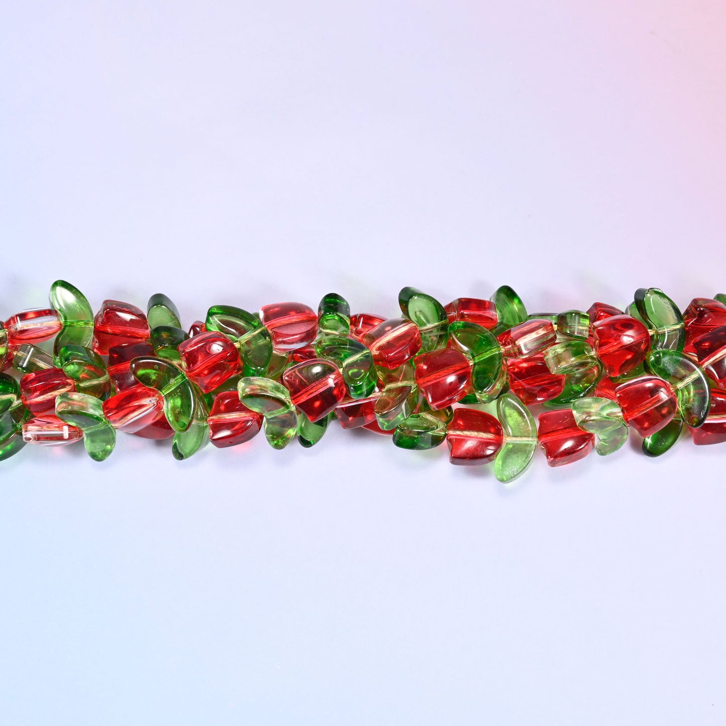 Close-up of a circular coil of red tulip and green leaf glass beads from a different angle, showing the alternating flower and leaf pattern.