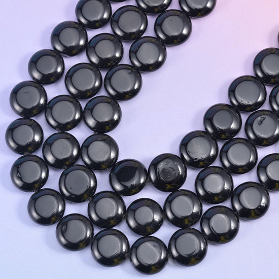 Two rows of black coin beads curving across the frame, drilled through the centre and strung on cord