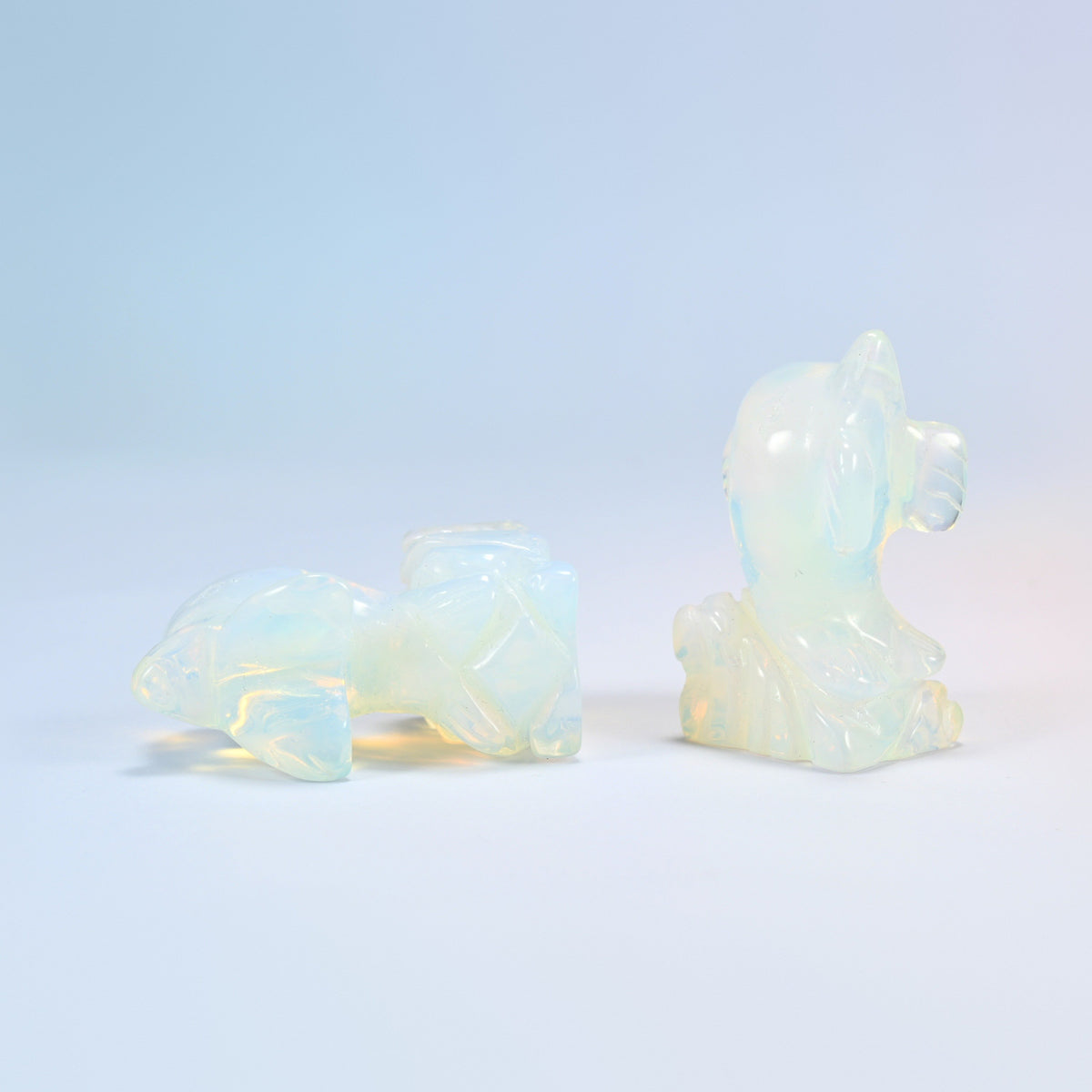 Opalite dolphin carving lying down beside a standing one, 2 inch man-made glass