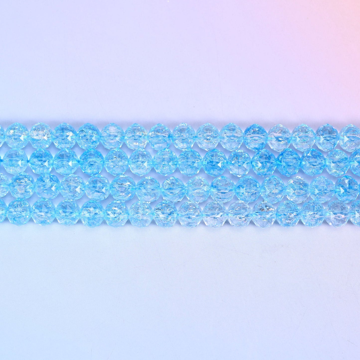 Transparent blue faceted round glass beads in clear sky-blue with fine crackled lines