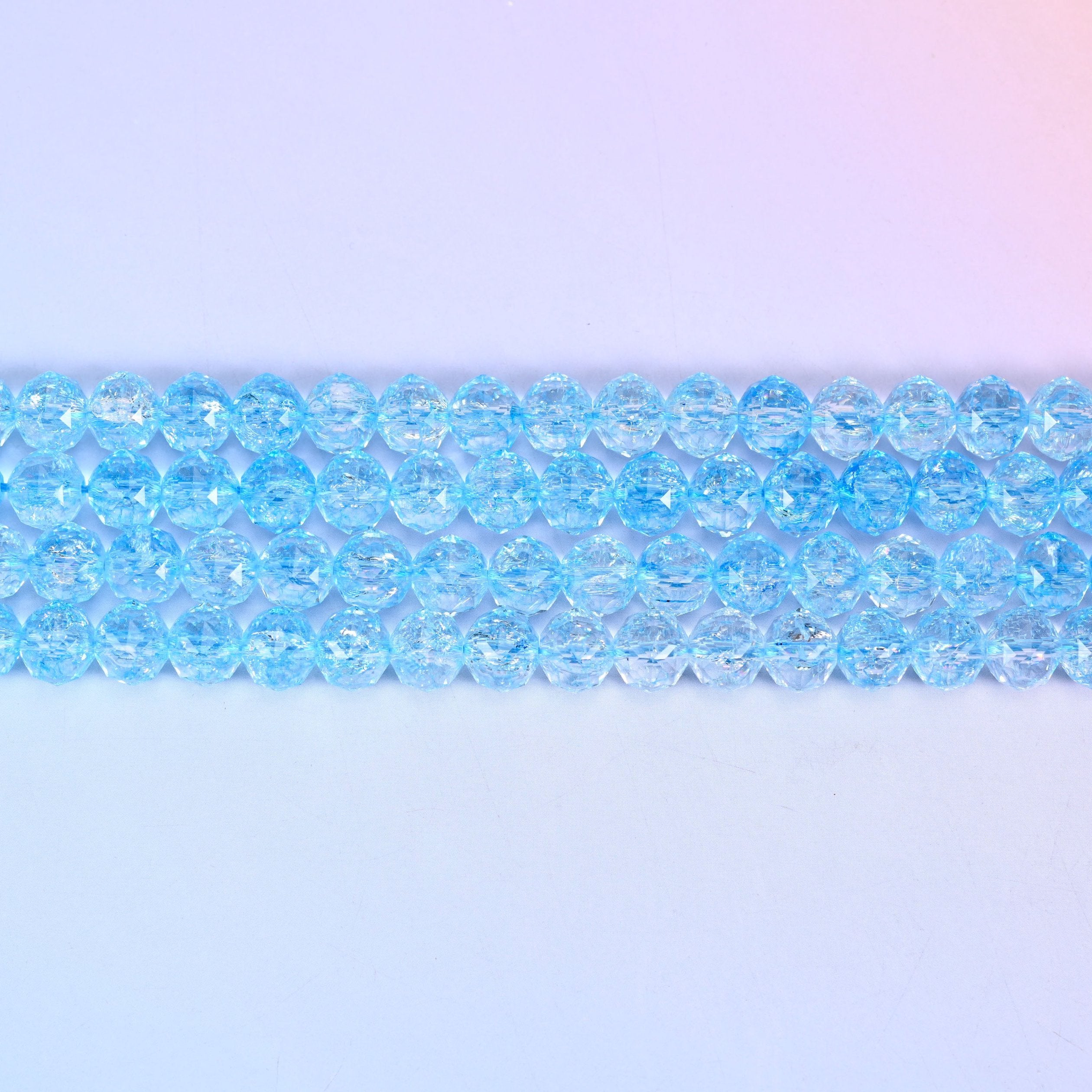 Transparent blue faceted round glass beads in clear sky-blue with fine crackled lines