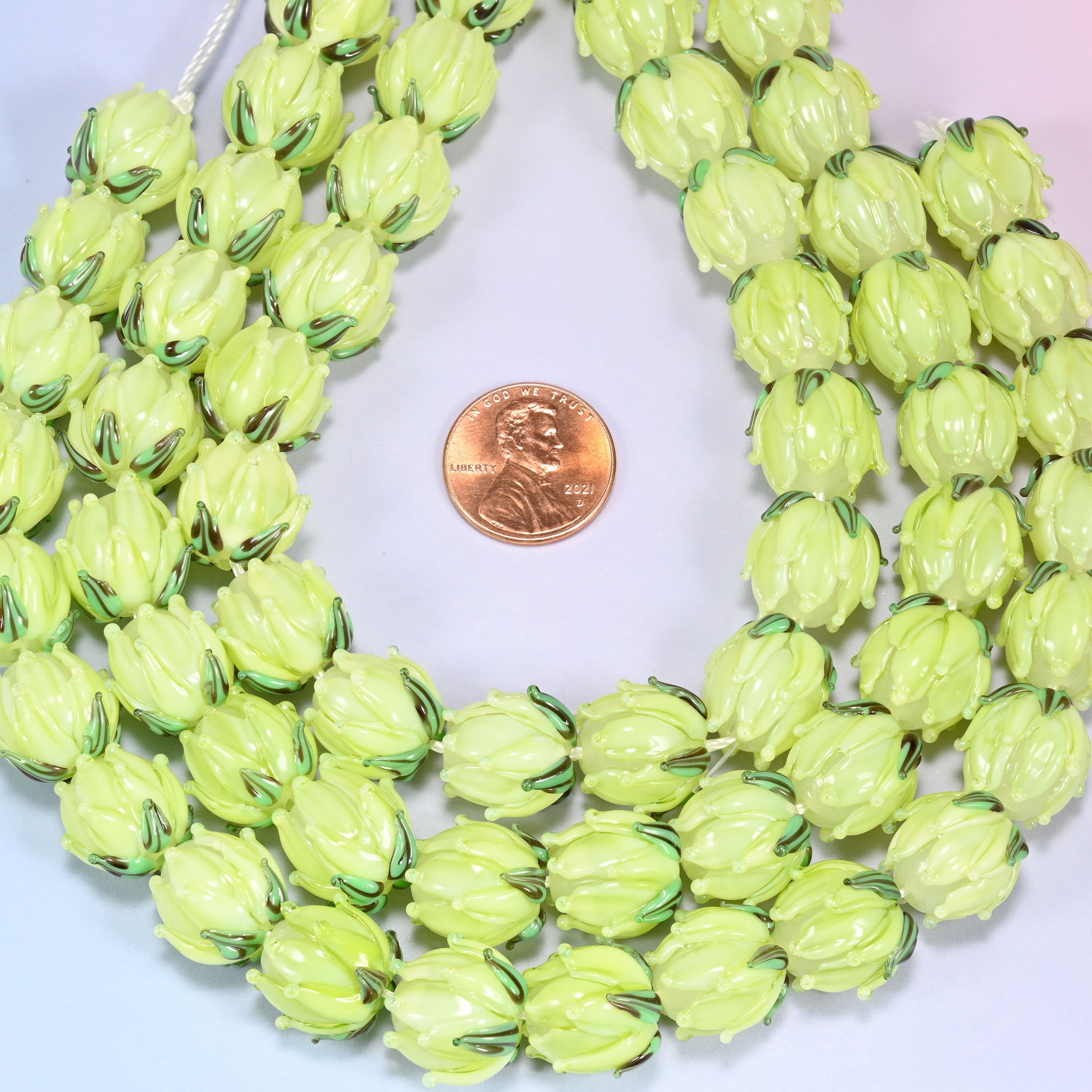 Lime green tulip bud-shaped lampwork glass beads, hand-formed with sculpted petal detailing that gives a realistic flower bud look, accented with a green leaf detail at the base.