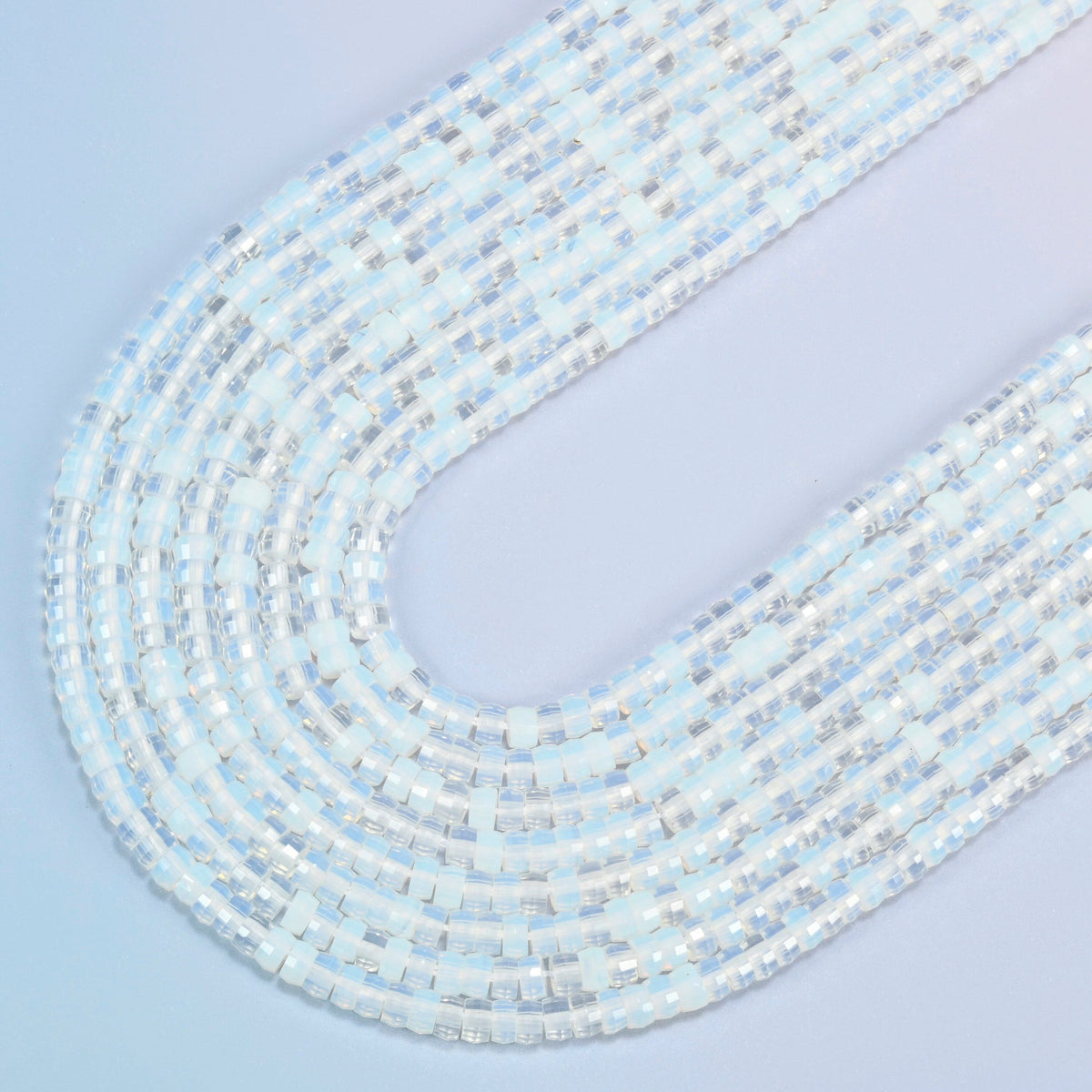 Opalite faceted heishi disc beads in several strands curved into a wide U, translucent milky white glass with a soft blue glow