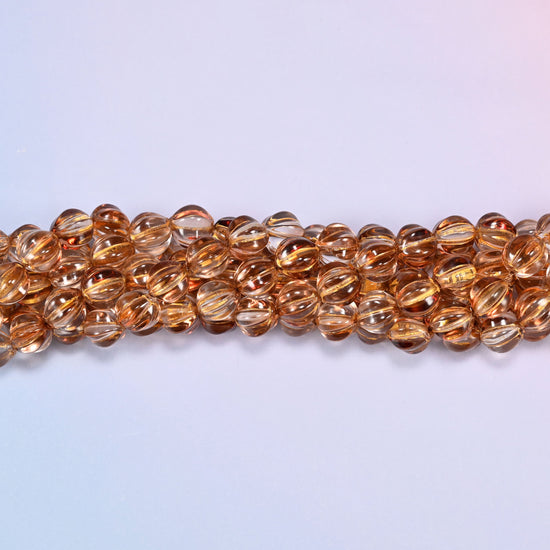 Brown pumpkin glass beads, 8mm melon rounds, strands laid in a gentle wave straight across the frame.