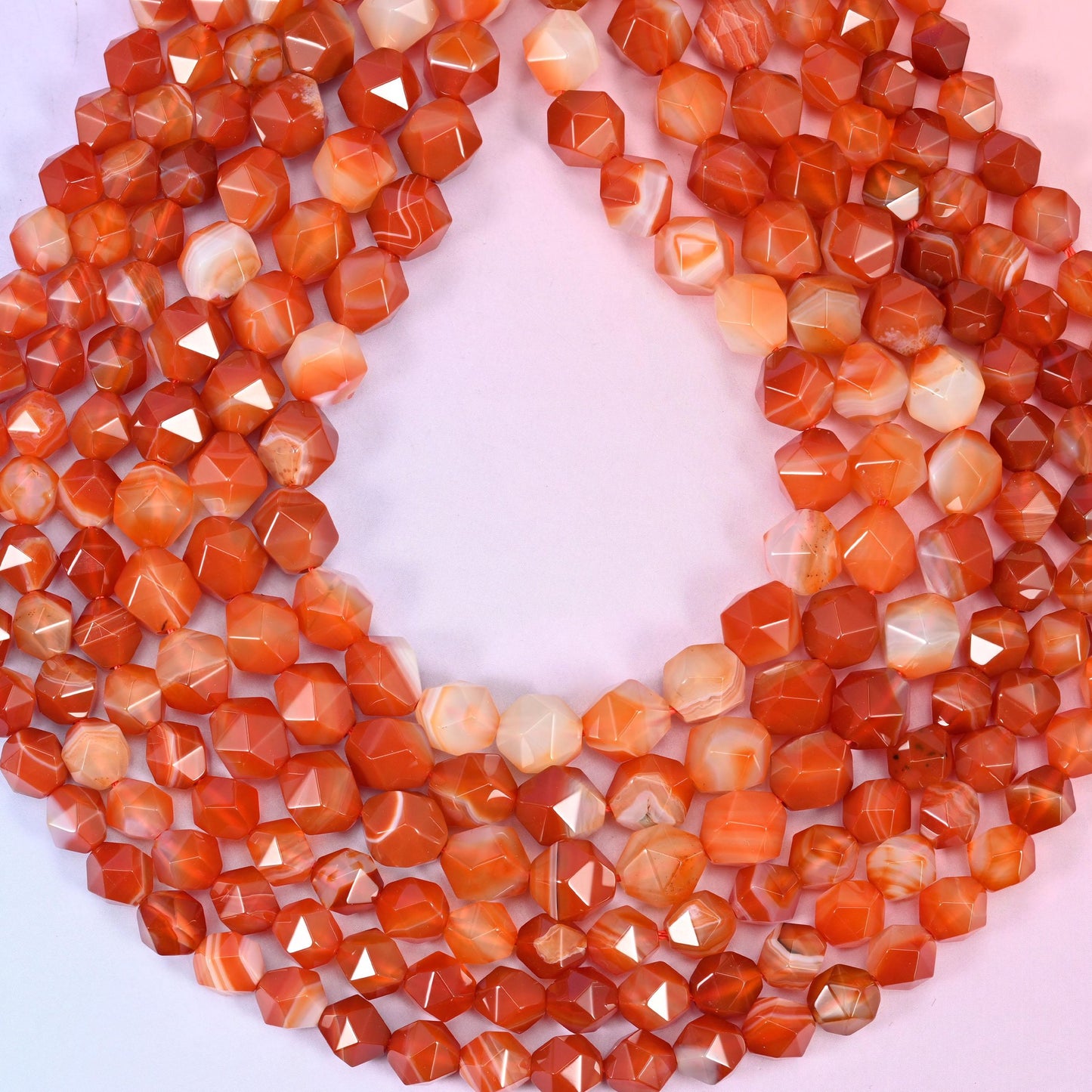 Dyed Red Stripe Agate beads coiled into a loop, star facets throwing highlights across the burnt orange and cream