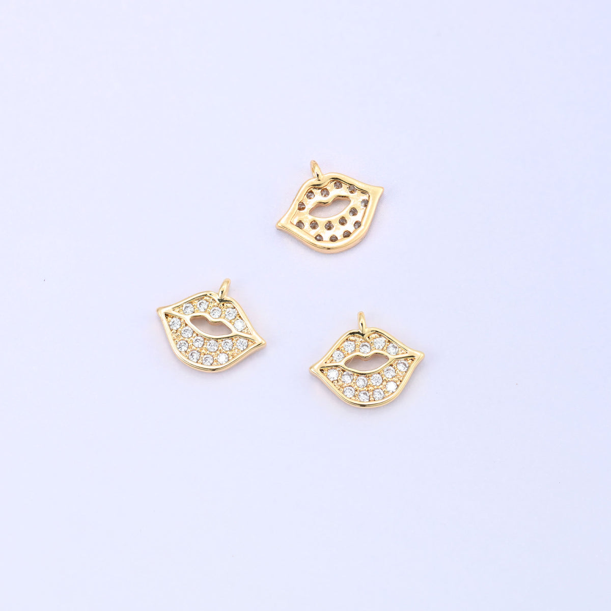 Small gold charms, three gold plated lip charms with one turned to show the plain back