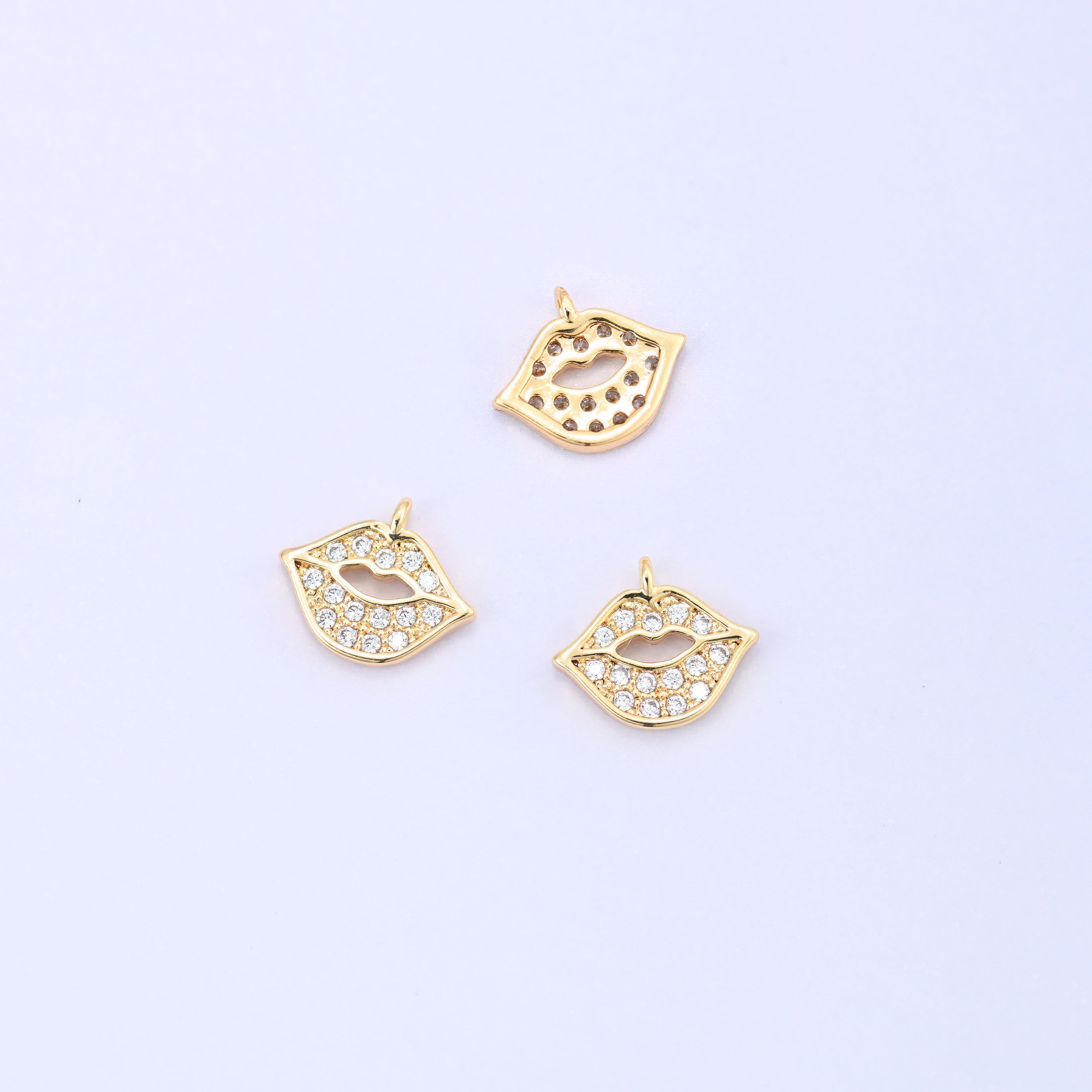 Small gold charms, three gold plated lip charms with one turned to show the plain back