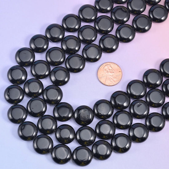 Obsidian coin strands looped around a US penny, an easy size reference for the 15mm discs