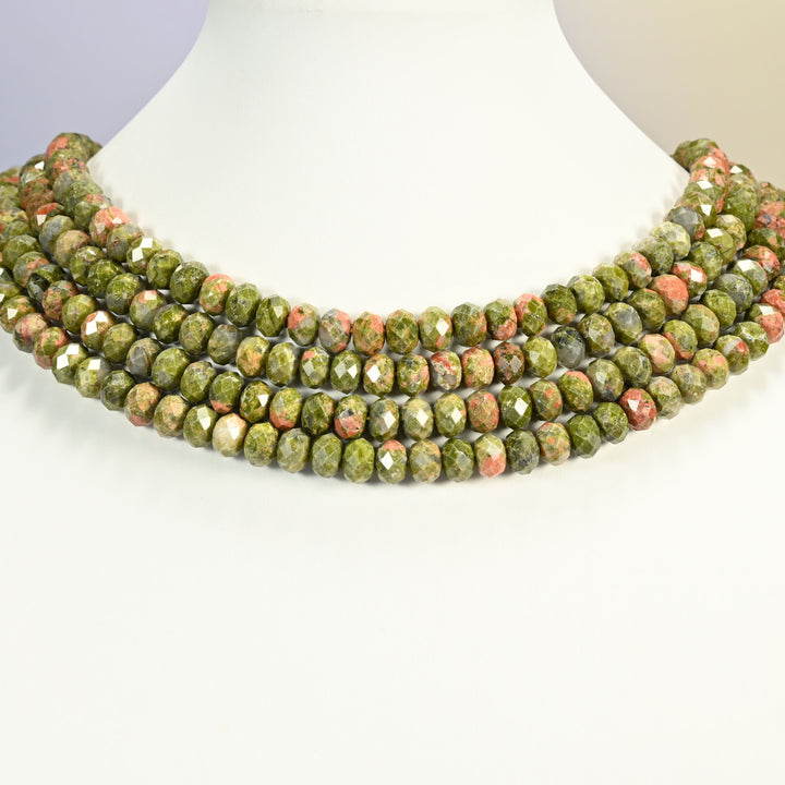 Unakite faceted rondelle strands arranged as a layered collar on a white display bust, green and pink tones across the neck