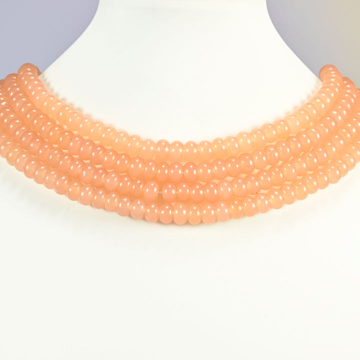 Peach Color dyed jade gemstone rondelle beads shown on a display bust as a layered collar, several strands stepping down in a row