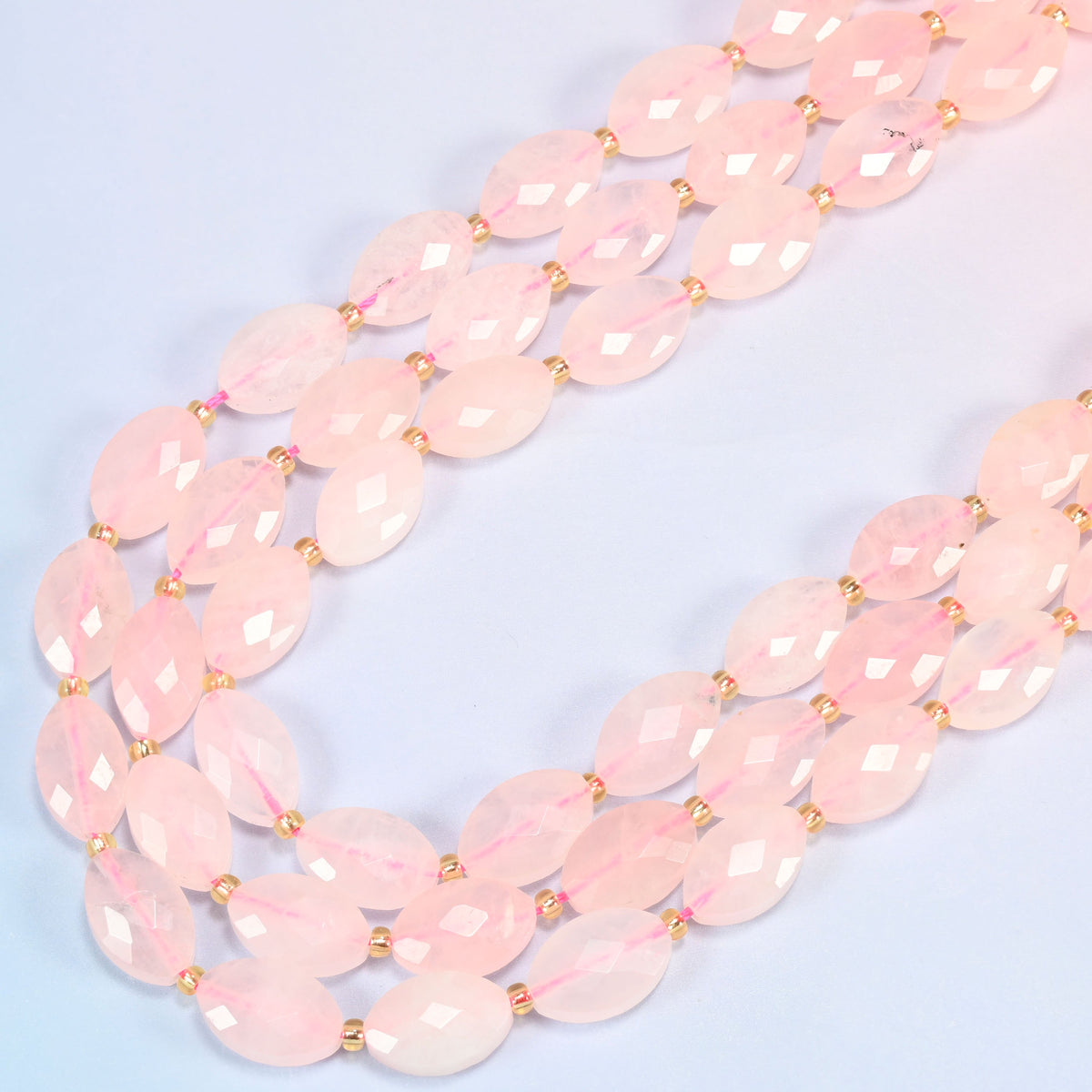 Rose quartz faceted flat oval beads in several strands curved into a wide U, soft blush pink stone