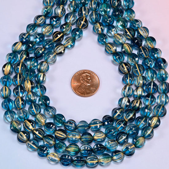 Dark blue gold pumpkin glass beads coiled into a ring, shown with a US penny in the open center for scale.