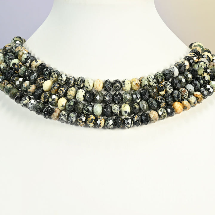 Old African howlite faceted rondelle strands arranged as a layered collar on a white display bust, black and cream speckled beads