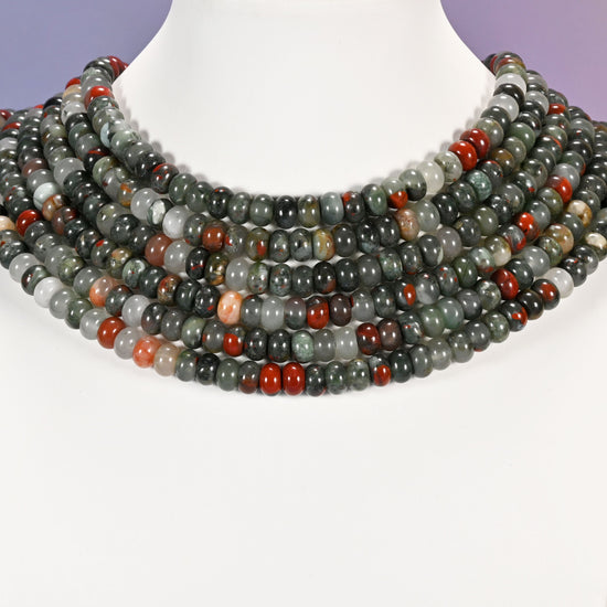 Multi-strand African Bloodstone necklace laid flat on a mannequin neck form against a lavender background.