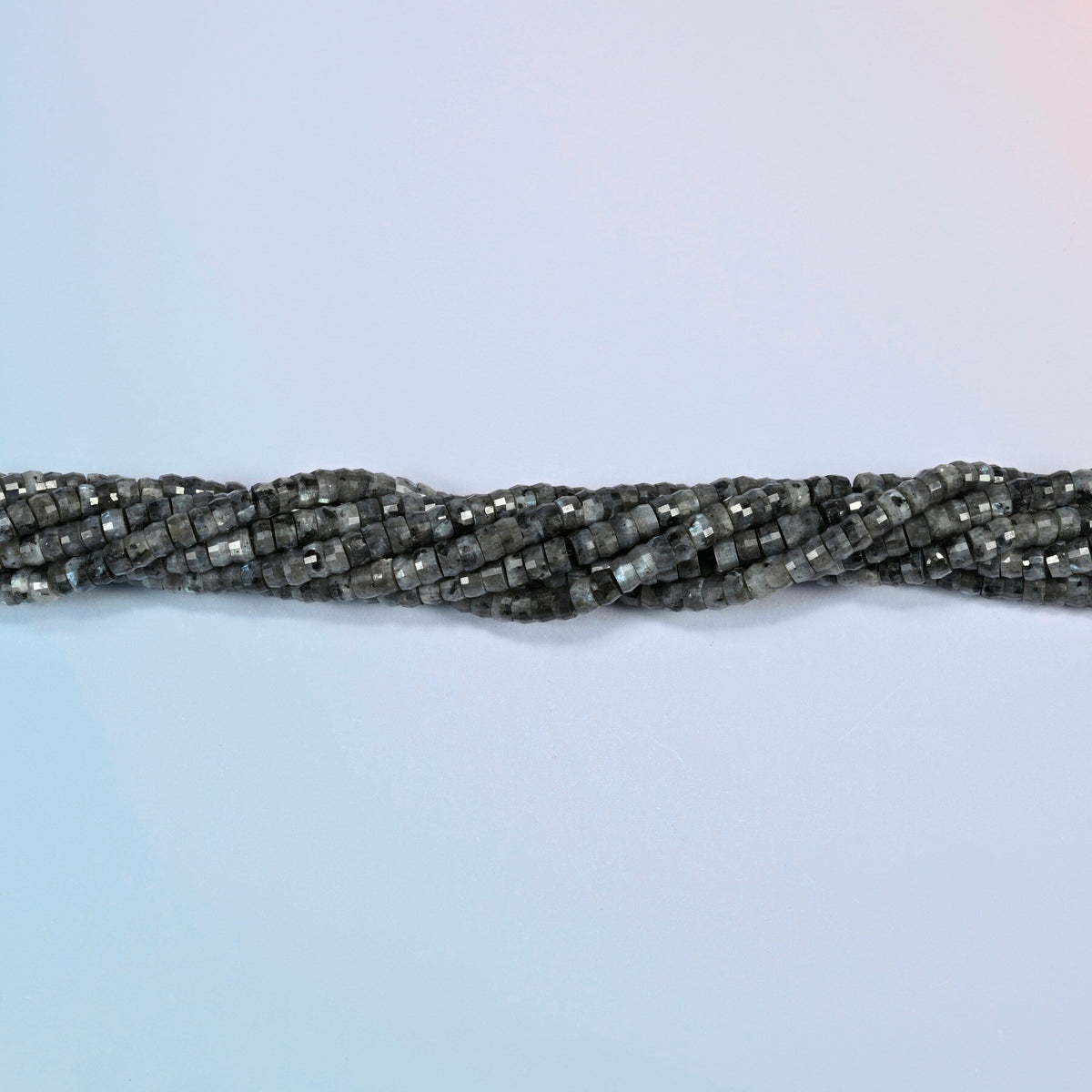 Strands of black labradorite faceted heishi disc beads twisted together in a horizontal row