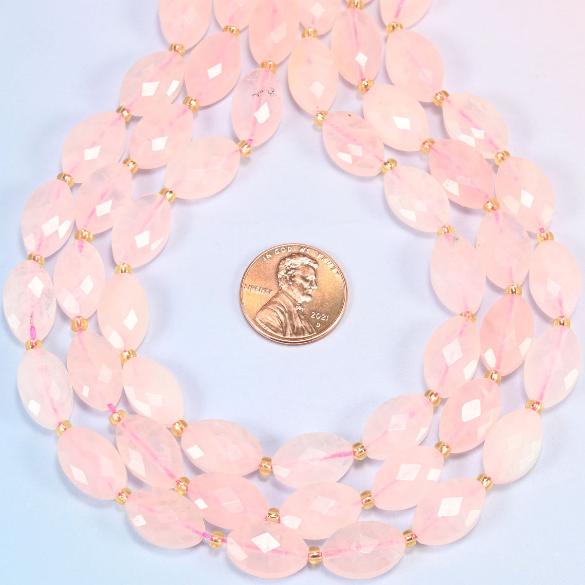 Rose quartz faceted flat oval strands formed into a teardrop loop around a US penny for scale
