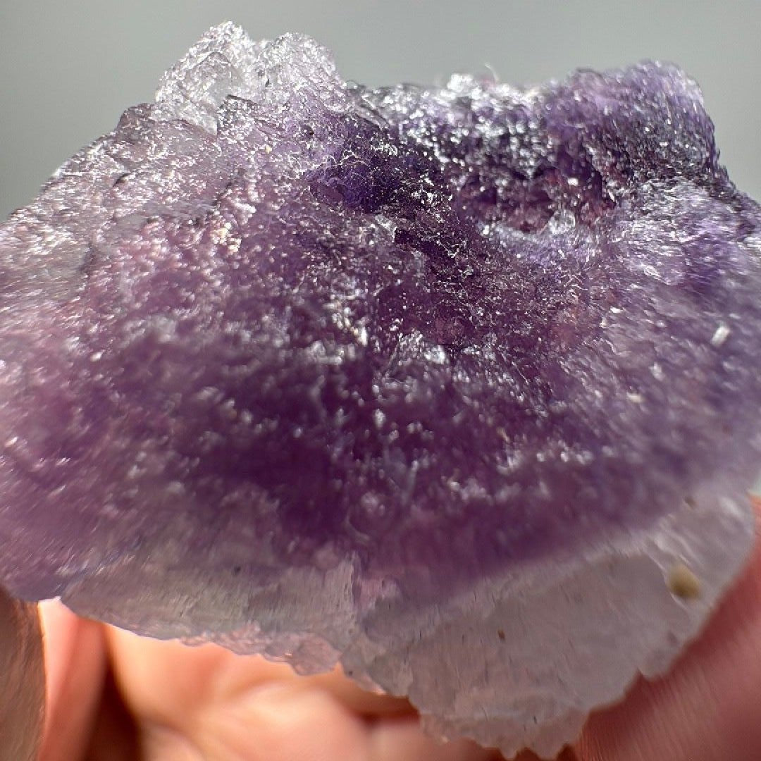 Close view of the purple crystal face, fine granular texture scattering the light