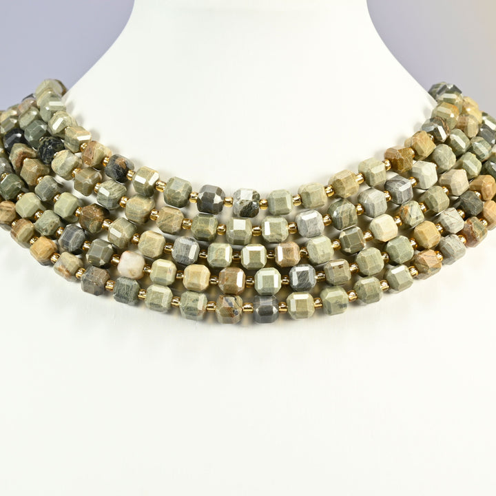 Silver leaf jasper faceted cube strands layered as a collar on a white display bust, gray-green, tan and cream cubes.