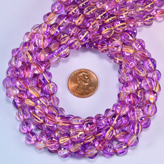 Purple gold pumpkin glass beads coiled tightly, shown with a US penny in the open center for scale.
