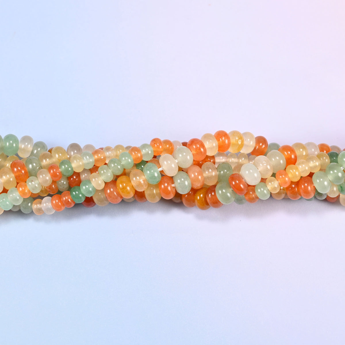 Gold Silk Jade gemstone rondelle beads twisted together, showing how the discs stack into a ribbed line