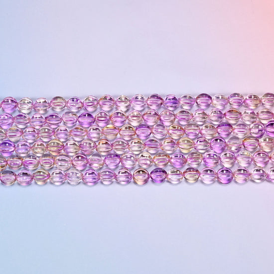 Close-up of 8mm clear purple gold pumpkin glass beads in four horizontal rows, showing the carved melon ribs.