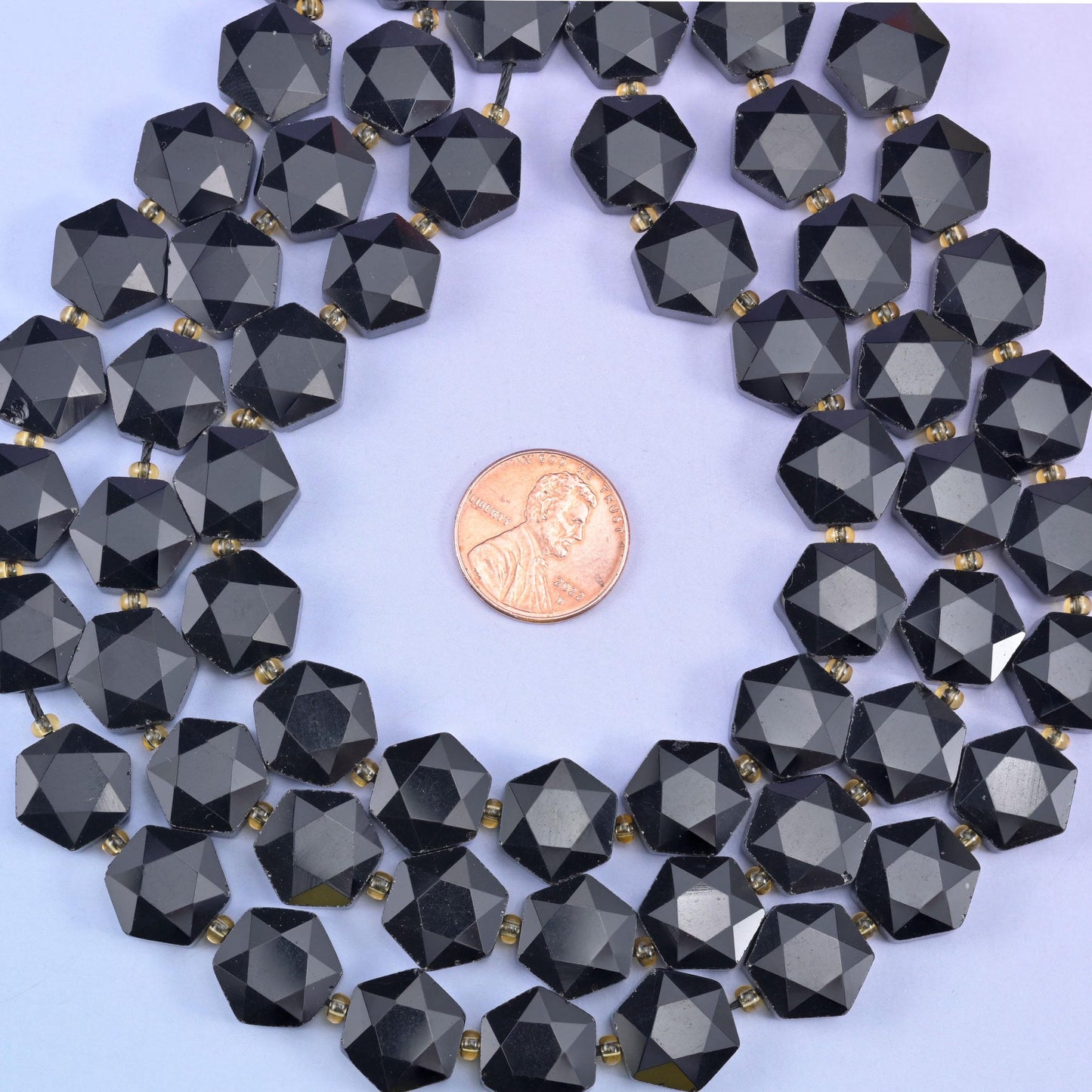 Coiled obsidian strand with a penny at the centre, showing the disc thickness from the side