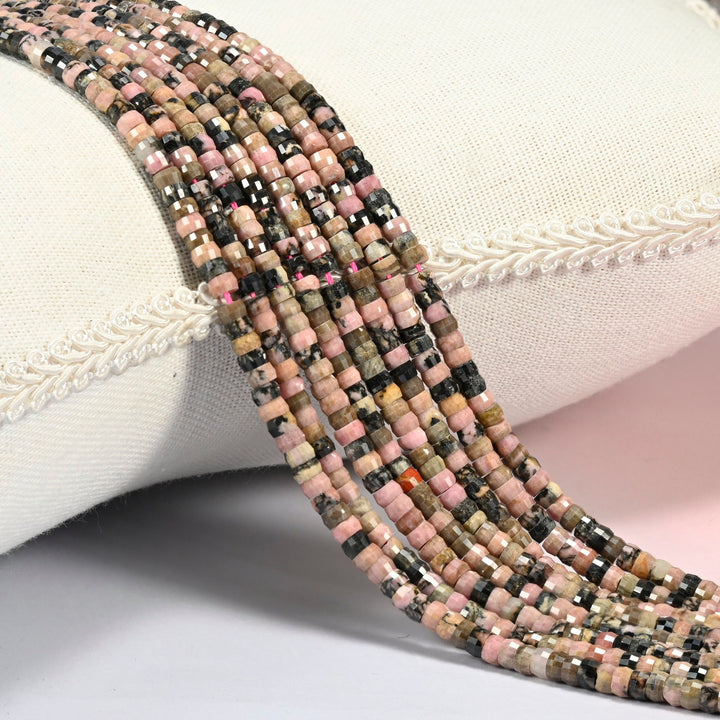 Rhodonite faceted heishi disc beads 2x4mm, several strands draped over a white cushion