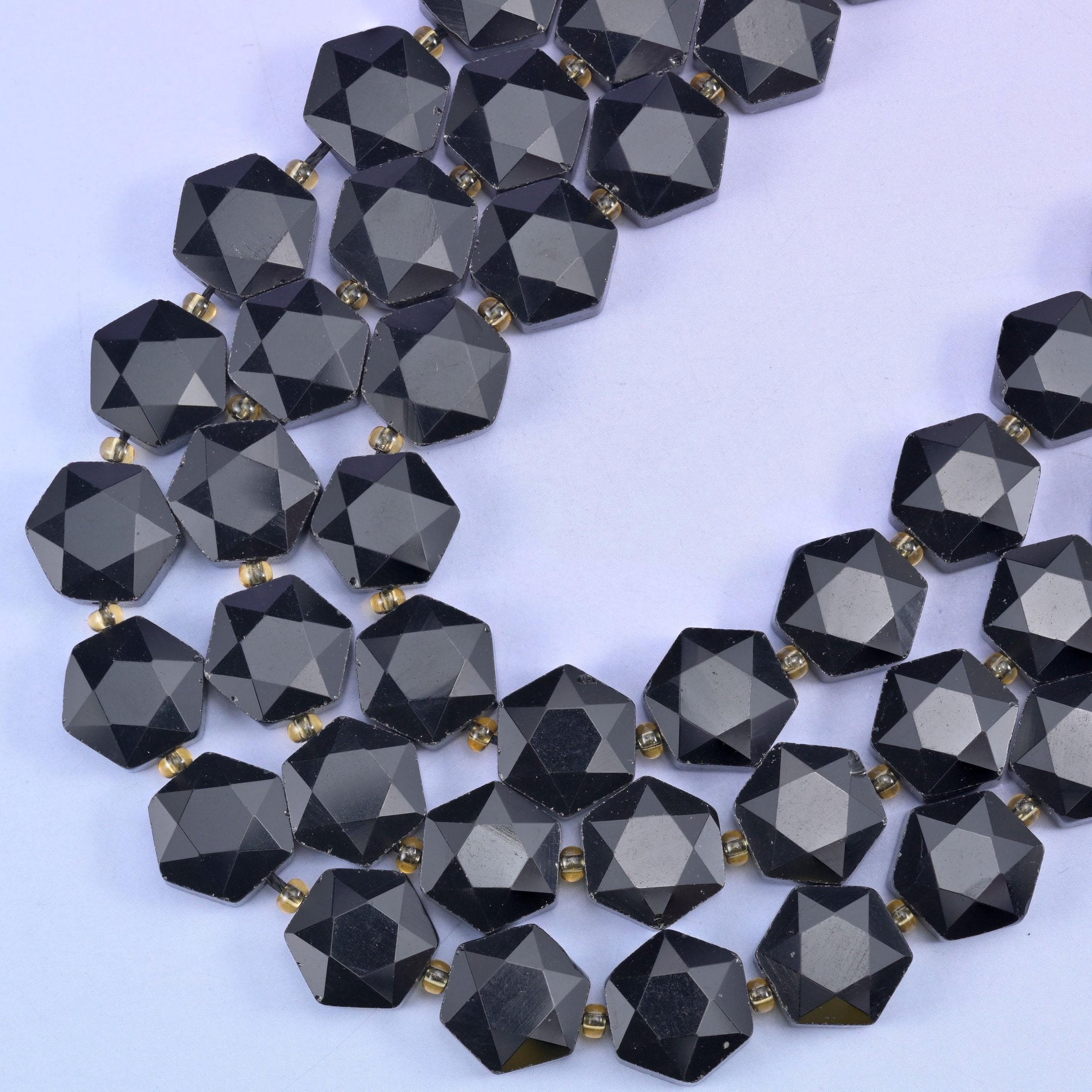 Strands curving into a V, small gold-tone spacers separating each faceted hexagon on the cord