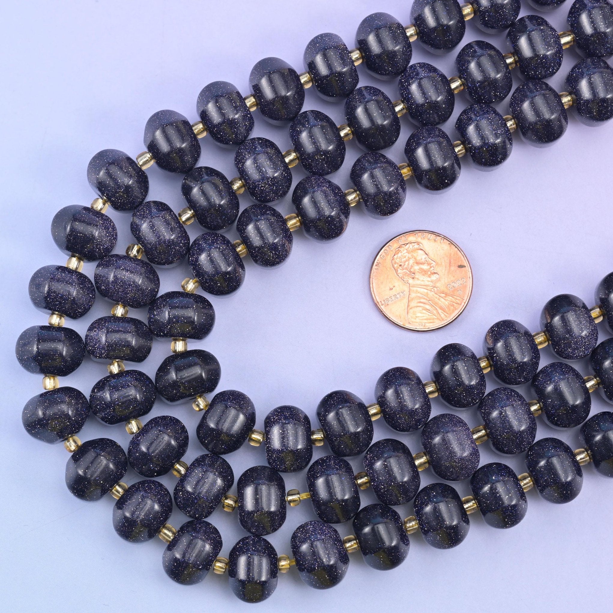 Blue Sandstone pumpkin beads curved around a US penny for size comparison
