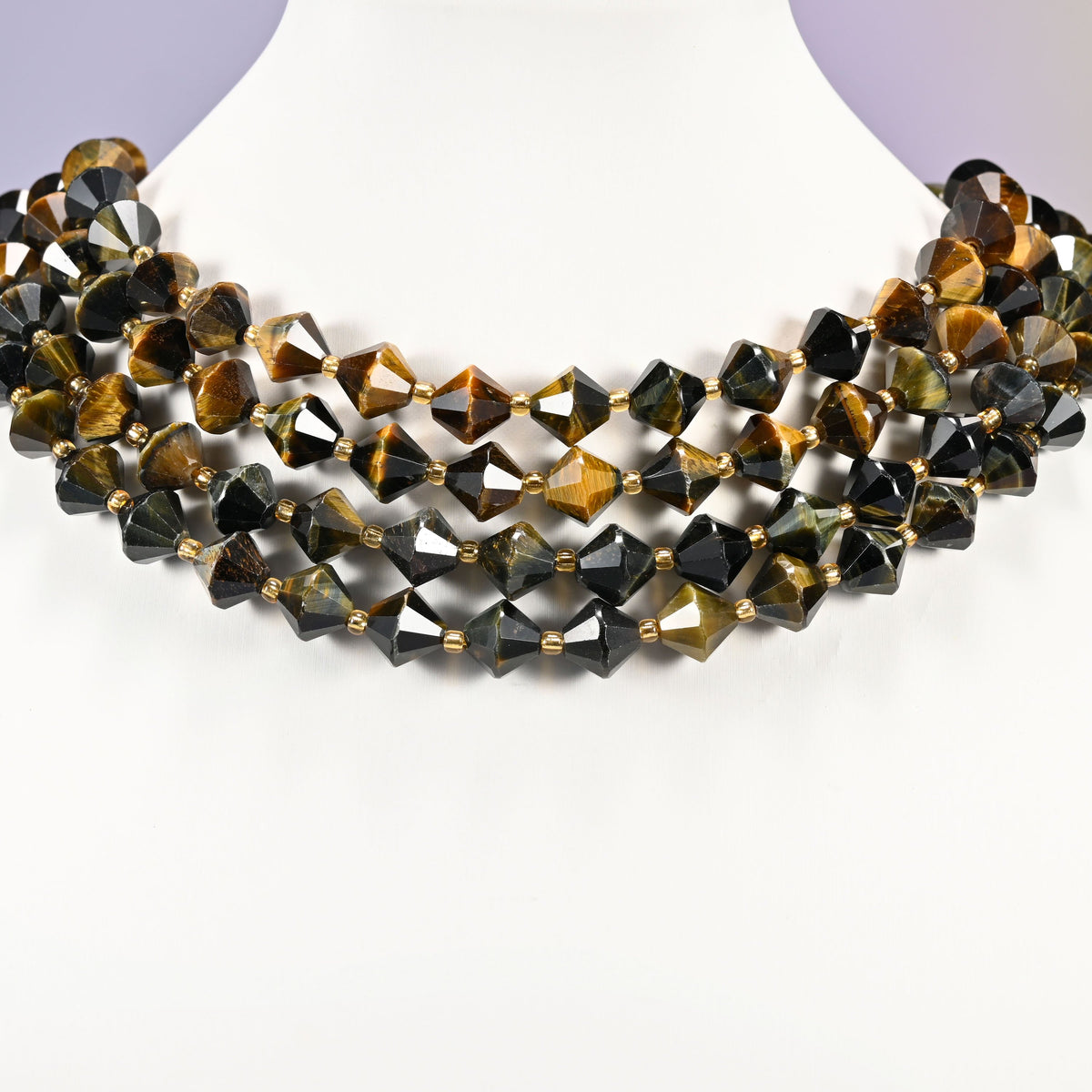 Strand of 10mm Iron Tiger Eye faceted bicone beads worn on a jewelry display bust, showing the necklace-length drape.