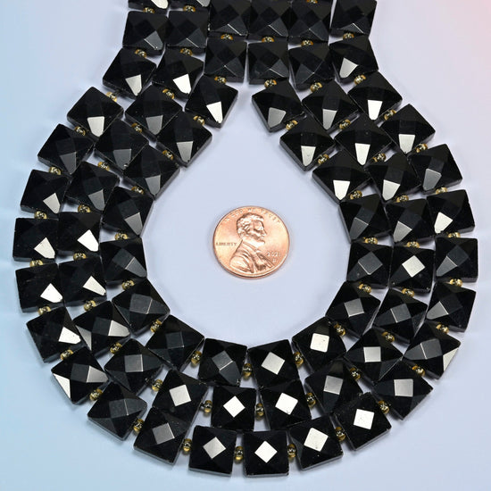 Natural black onyx faceted flat square strands formed into a teardrop loop around a US penny for scale