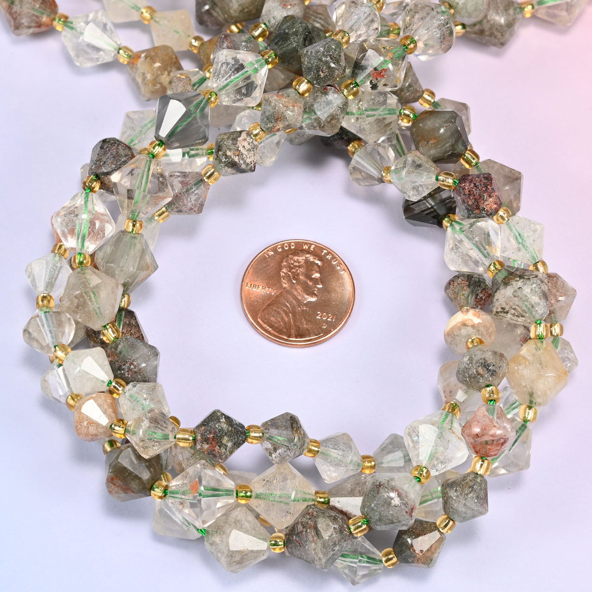 Close-up of Green Phantom Quartz faceted bicone beads, 8mm and 10mm, coiled into a circle, highlighting the internal green phantom inclusions.