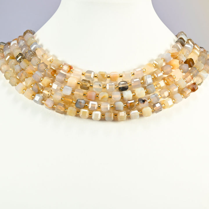 Yellow agate faceted cube strands arranged as a layered collar on a white display bust, honey, cream and gray beads across the neck