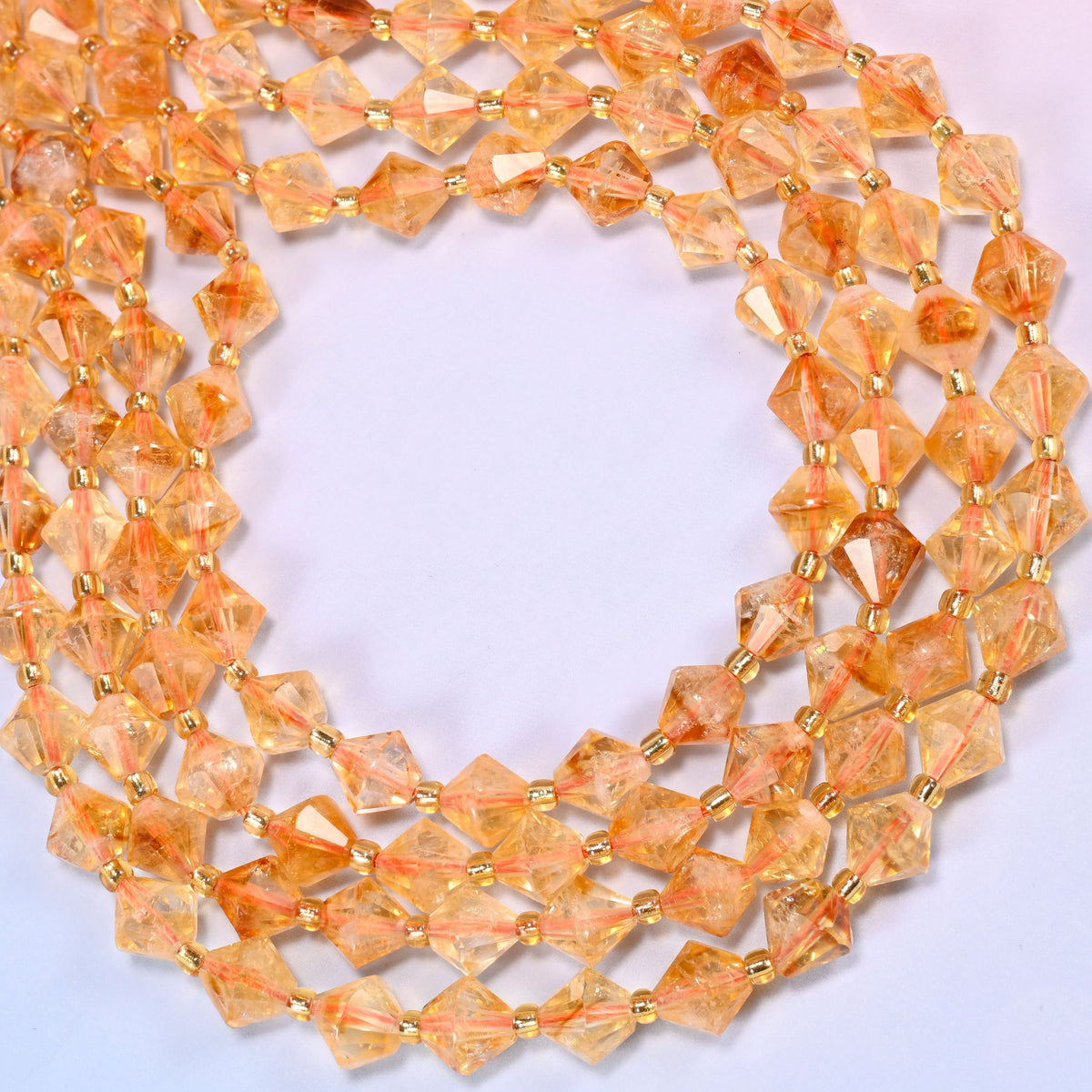 Citrine bicone beads formed into a wide open ring, faceted sides picking up highlights around the curve.