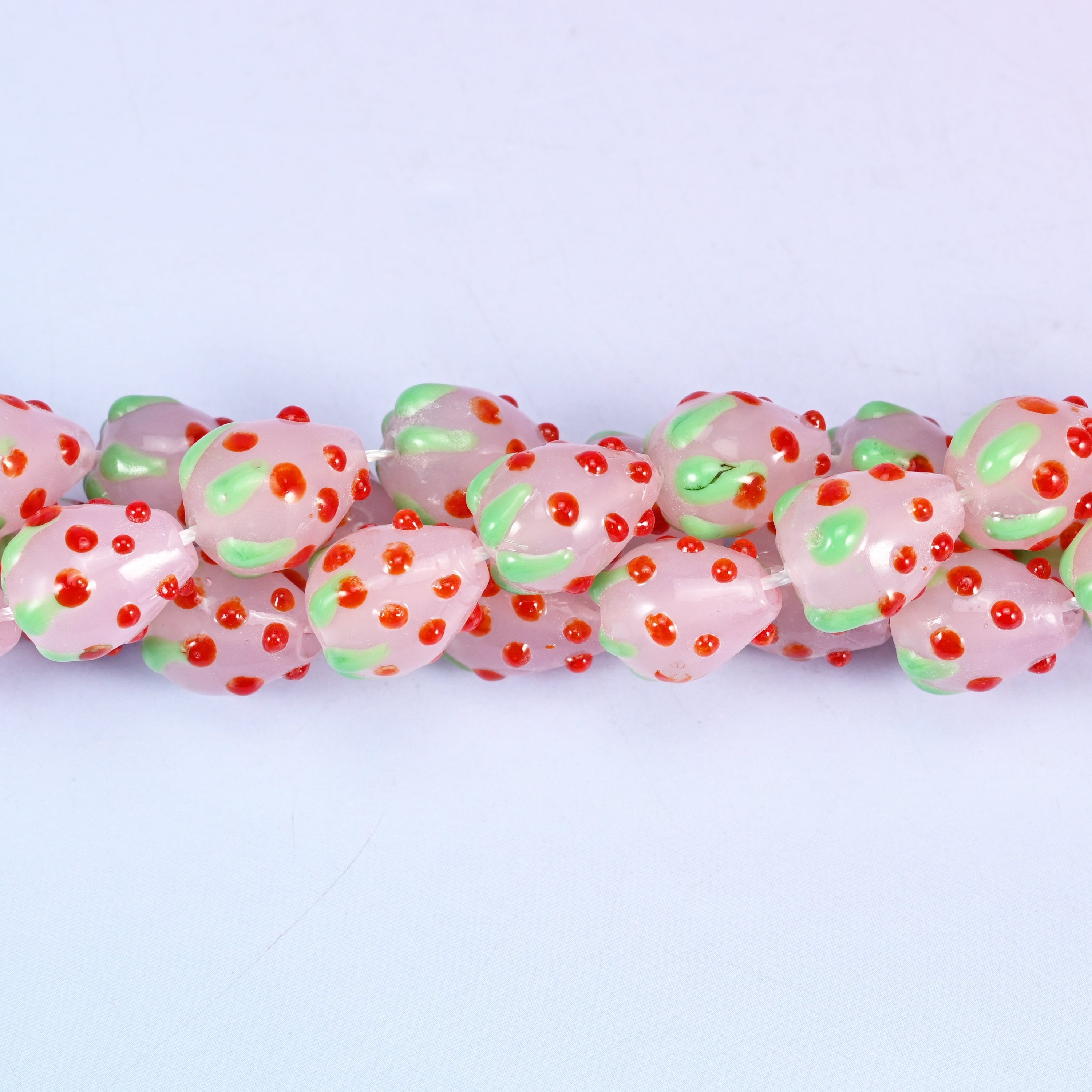 Man-made glass strawberry beads in pink, red and green