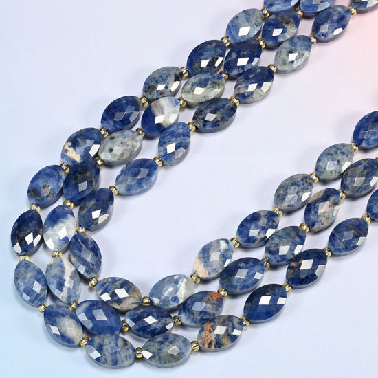 Orange sodalite faceted flat oval beads in several strands curved into a wide U, denim blue with peach-orange patches