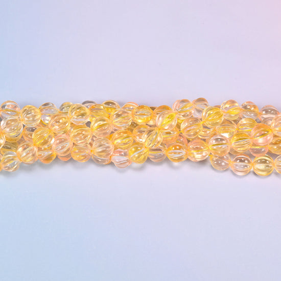Yellow clear pumpkin glass beads coiled into a ring, shown with a US penny in the open center for scale.