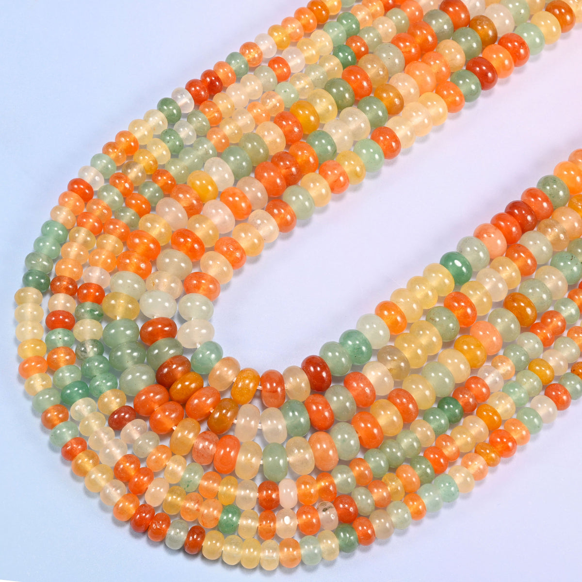 Gold Silk Jade gemstone rondelle beads curving in a wide U across the frame, 4x6mm and 5x8mm strands together
